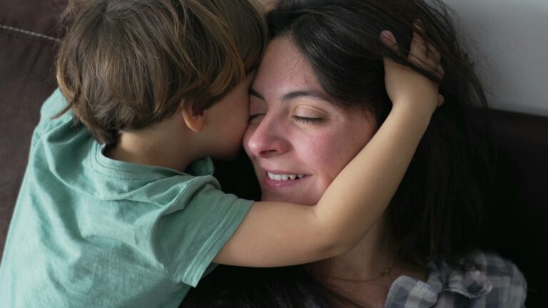 Barn som kramar om en trött mamma i sängen.