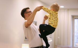 Barn som klättrar i sin pappas famn.